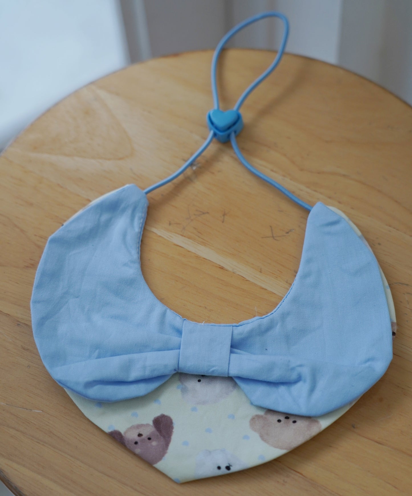 Light blue fabric collar with a bow on a wooden surface