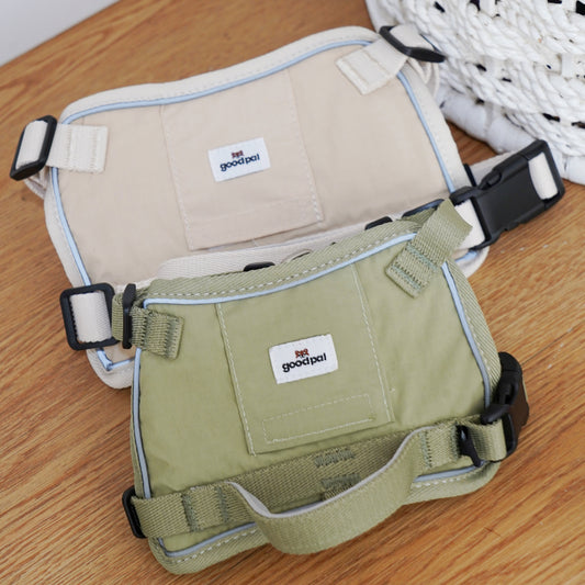 Two dog harnesses, one beige and one green, on a wooden surface with a white basket in the background.