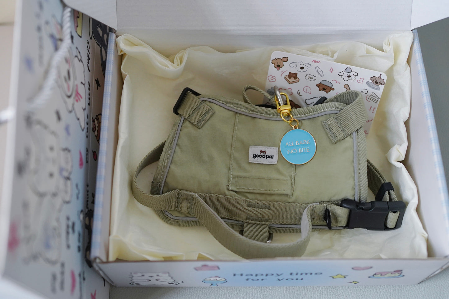 Dog harness in a box with a blue tag and packaging details.